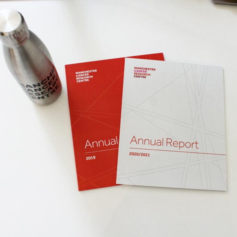 Two previous annual reports from 2019 and 2020/2021 on a table with an MCRC water bottle