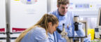 Two researchers in a lab using a microscope