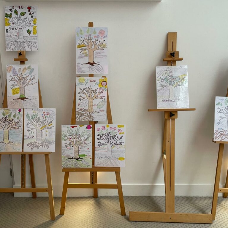 Several wooden stands display drawings of trees with words around them. This is a narrative tool used to explore an individual's life story.