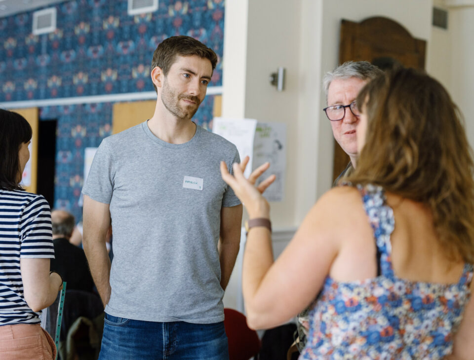 Woman talking and two men listening.