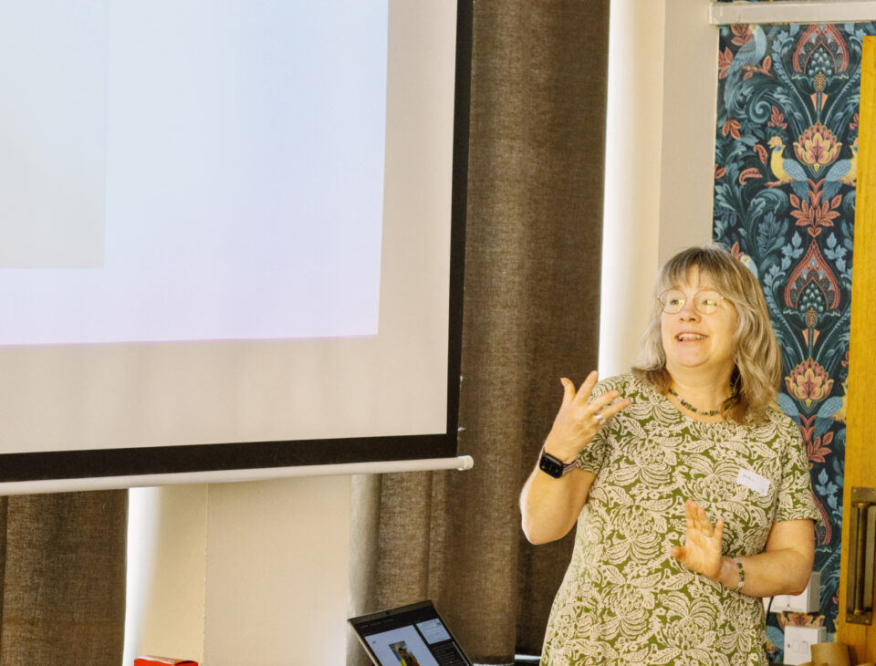 Woman speaking in front of a powerpoint presentation
