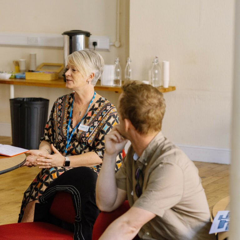 Woman speaking and gesticulating with hands. Man faced away from the camera listening to the woman.