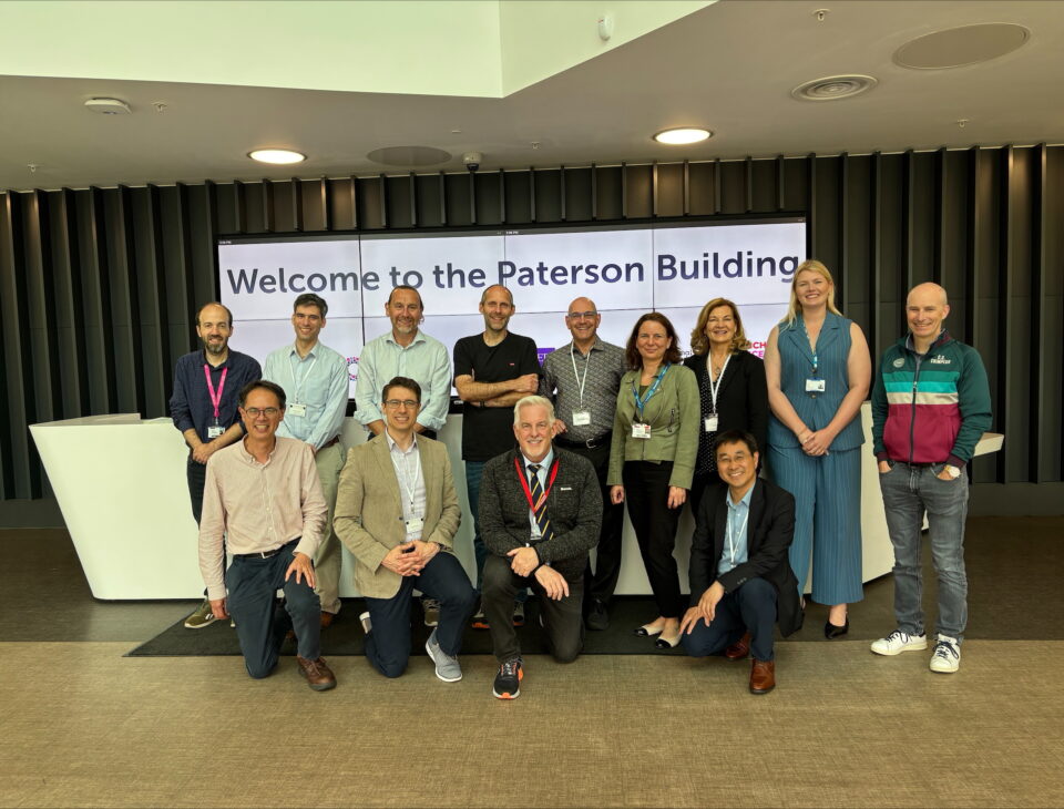 Rob with colleagues from the Princess Margaret Cancer Hospital in front of a sign saying 'Welcome to the Paterson Building'